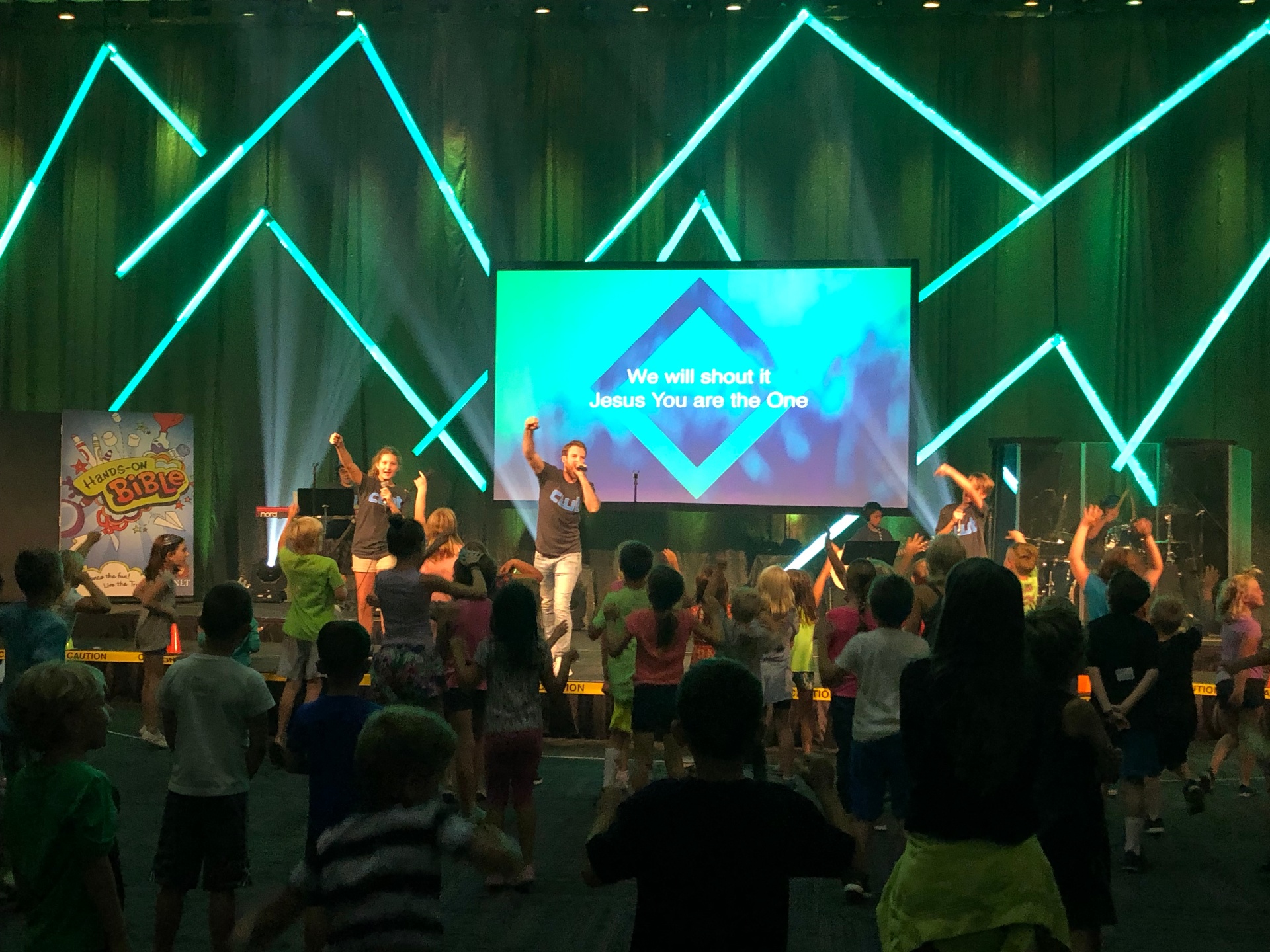 Kids worshipping with leaders on stage