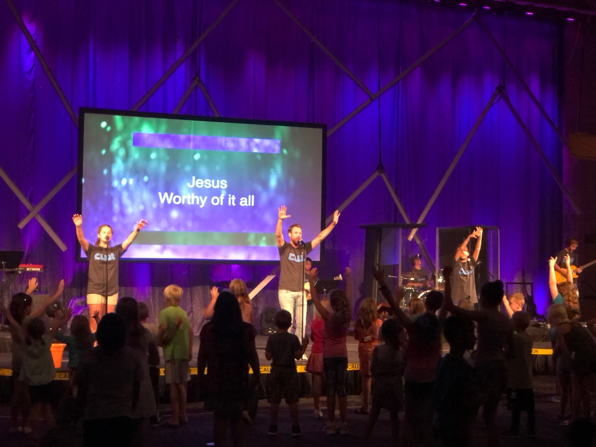 Kids worshipping with hands raised during a service